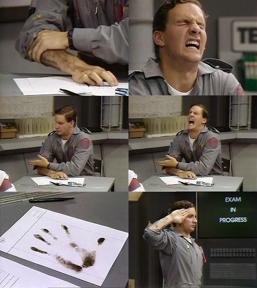 Rimmer placing his ink covered hand on exam paper in Red Dwarf